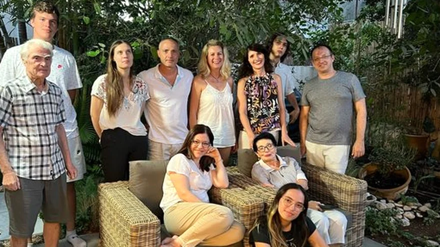Three generations of one family photographed together in a garden, the oldest sitting in the middle
